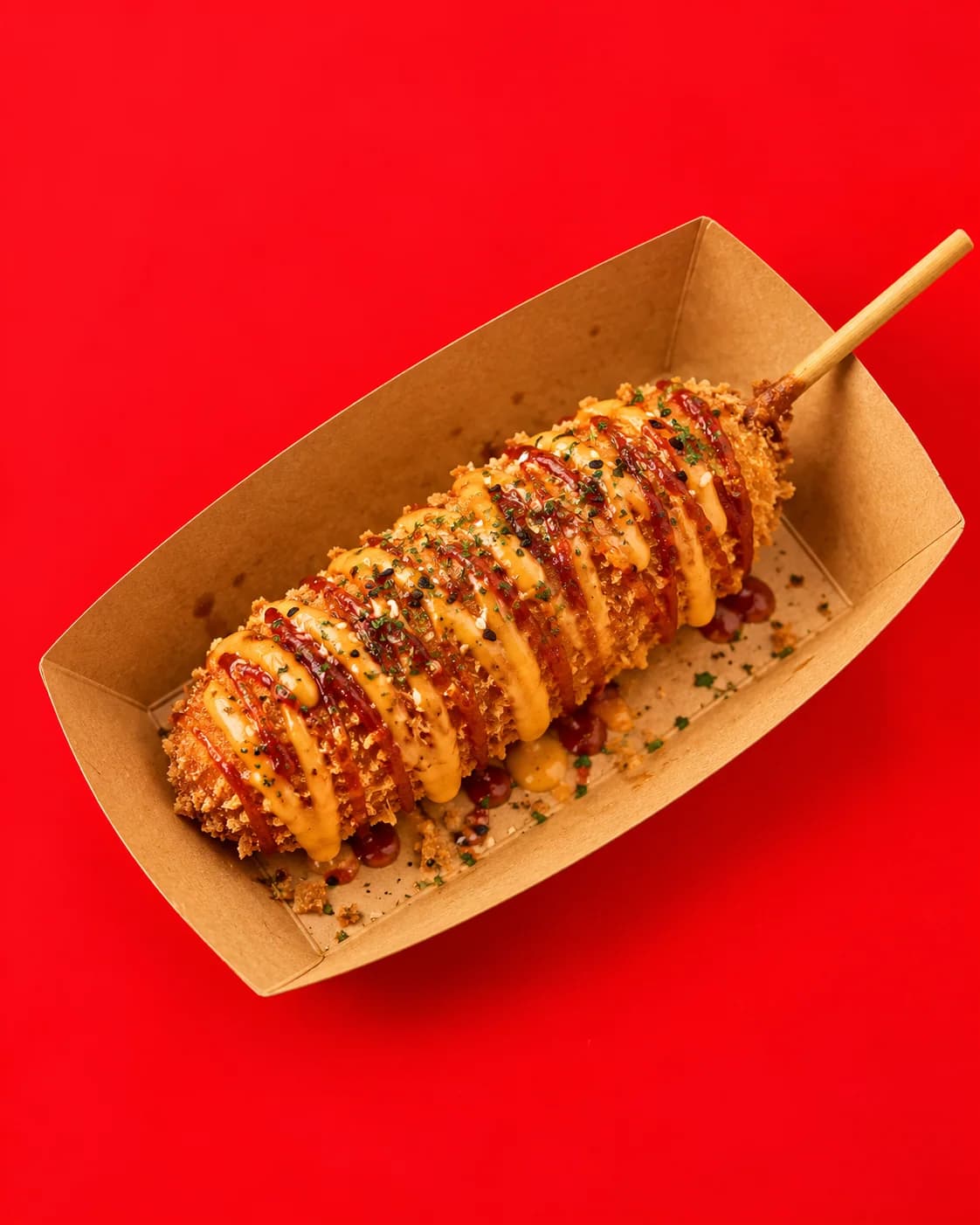 Crumb-coated Korean cheese corn dog drizzled with cheese and chilli sauce