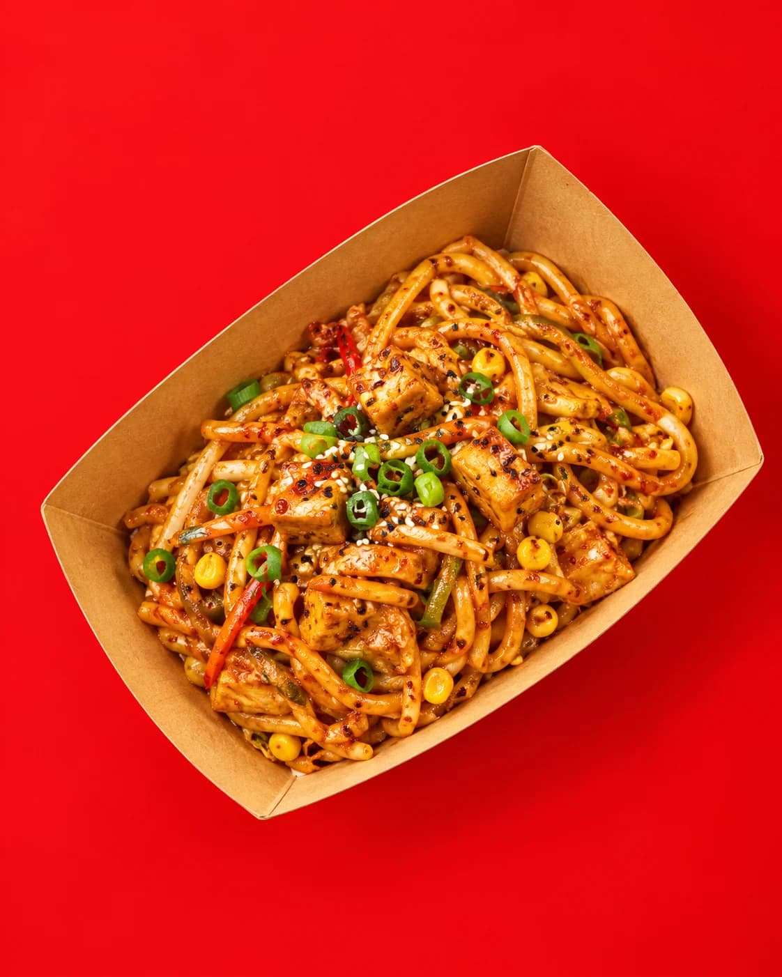 Spicy red udon with tofu, corn and spring onion in a kraft tray