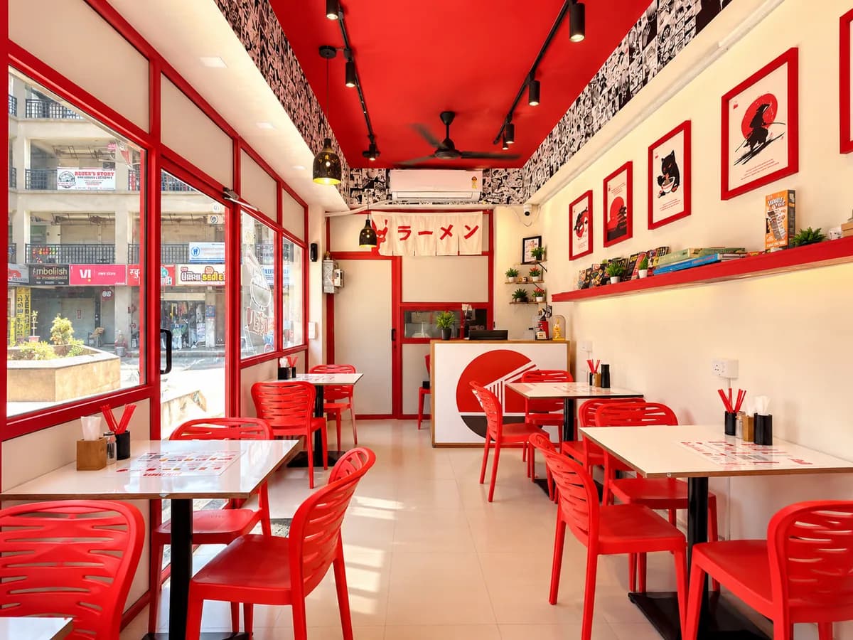 Bright SATO Naroda dining room with red chairs, framed art and a ラーメン banner