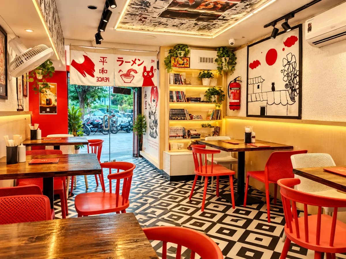 SATO Prahlad Nagar dining room with red chairs, black-and-white tiled floor, manga ceiling and a ラーメン noren curtain