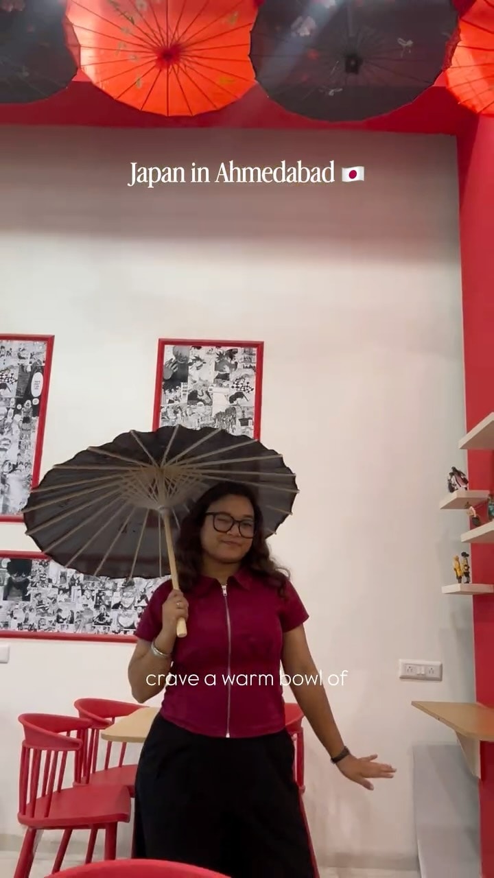 Guest with a paper umbrella under SATO's parasol ceiling, titled Japan in Ahmedabad