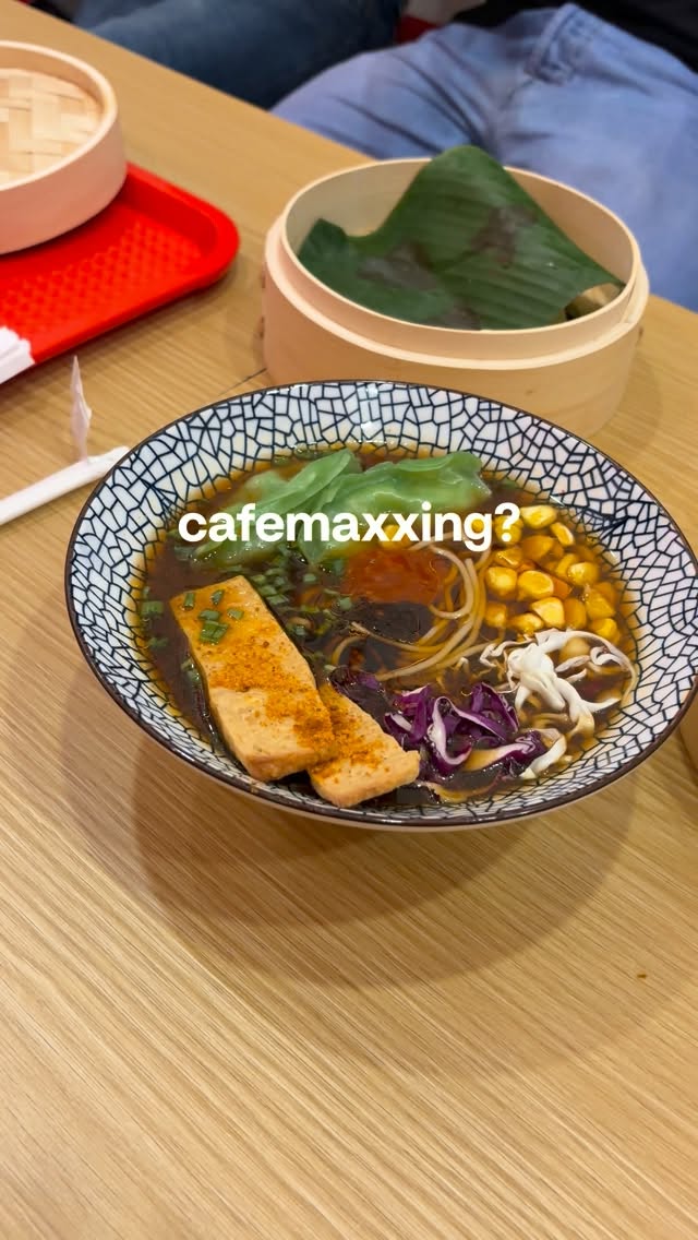 Bowl of SATO ramen with tofu, corn and greens beside bamboo steamers